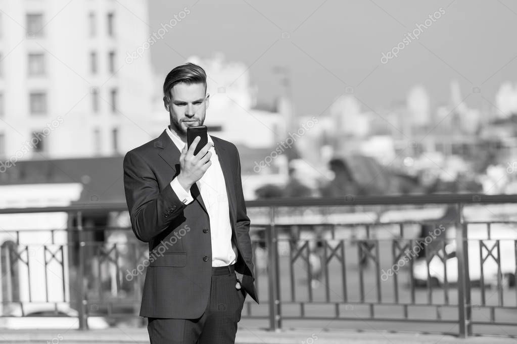 Businessman with smartphone on sunny terrace. Man in business suit with mobile phone outdoor. Business communication, new technology and sms. Modern life and business lifestyle