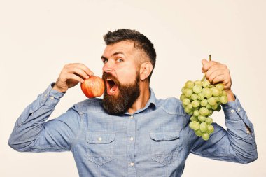 Aç suratlı şarap üreticisi üzüm ve meyve tutuyor..