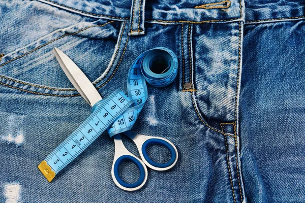 Meça a fita em volta da tesoura metálica no tecido de calça — Fotografia de Stock