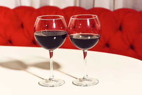 Dois copos de vinho tinto, bebida alcoólica, bebida, servido em mesa branca no café ou bar no sofá fundo . — Fotografia de Stock