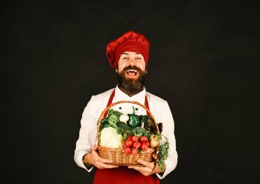 Sakallı adam siyah arka planda sebze tutuyor..