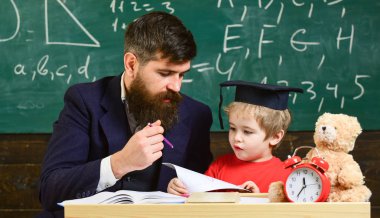 Öğretmen, evde tek tek çocuk çalışmaları. Sakal, oğlum, küçük çocuk öğretmen öğretir Peder. Öğretmen ve öğrenci kolej, kara tahta arka plan içinde. Bireysel eğitim kavramı