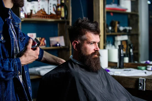Hipster client getting haircut. Barber with hair clipper works on hairstyle for bearded man barbershop background. Haircut process concept. Barber with hair clipper in hand finished trimming — Stock Photo, Image