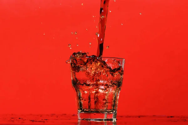 Respingo de água em vidro para uísque no fundo vermelho, espaço de cópia . — Fotografia de Stock