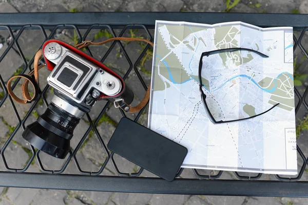 Retro camera, sunglasses and mobile phone lying on city guide — Stock Photo, Image