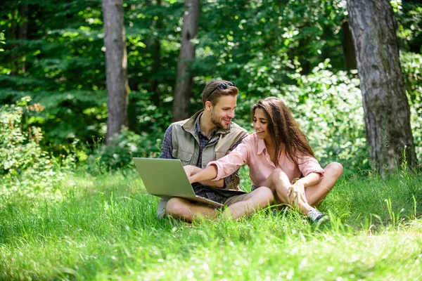 Closer to nature. Modern technologies give opportunity to be online and work in any environment conditions. Couple youth spend leisure outdoors with laptop. Man and girl looking at laptop screen