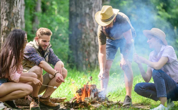 Gli amici della società preparano arrosto marshmallows snack natura sfondo. Attività di campeggio. Torrefazione marshmallows popolare attività di gruppo intorno al falò. Azienda giovani campeggio foresta torrefazione marshmallows — Foto Stock