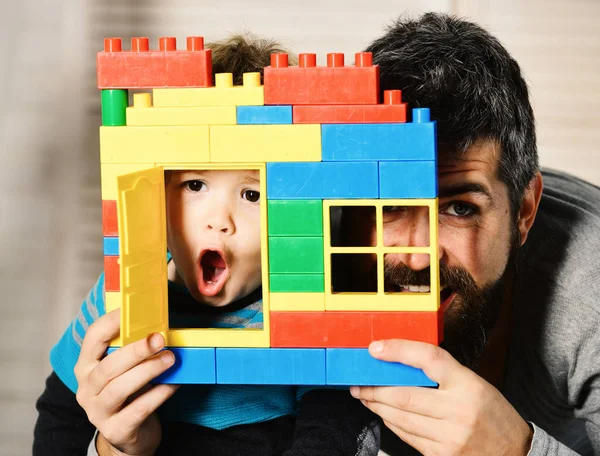 Pai e filho com rostos surpresos olham pela janela — Fotografia de Stock