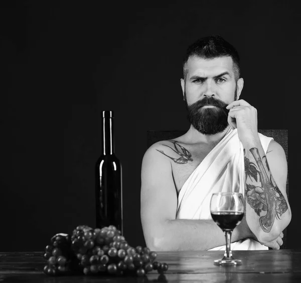 Sommelier tasting wine. Man with beard near glass of alcohol on brown background.