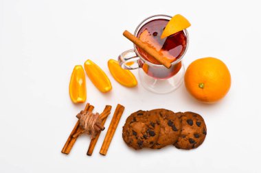 Cam mulled şarap veya içki yakınındaki beyaz arka plan üzerinde sulu turuncu meyve ile kapatın. İçki veya tarçın, turuncu meyve ve çerez çikolata damla içecek. Sonbahar içecek konsepti