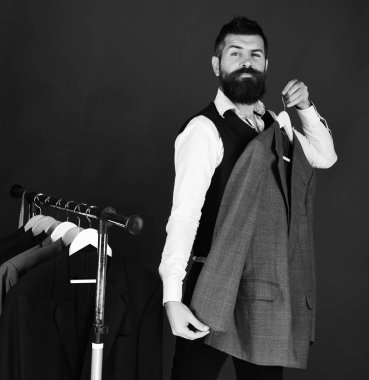 Kurnaz yüzlü bir işadamı yeşil arka planda ceketini deniyor..