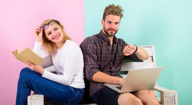 Kız koca freelancer laptop ile çalışırken hayatını tadını çıkarın. Adam serbest üzerinde Internet teknolojileri uzmanı çalışıyor. Serbest faydaları. Yüz kitap çalışan erkeğin yakınındaki okuma gülümseyen kadın