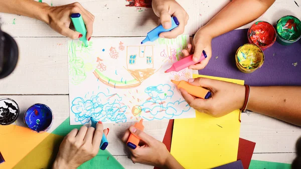 Artistas mesa de madeira com tintas e papel colorido. Conceito de arte e ideia. Mãos segurar marcadores coloridos — Fotografia de Stock