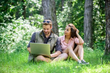 Adam ve yeşil çayır laptop ile çalışan kız. Serbest fırsat. Modern teknolojileri herhangi bir çevre koşullarında çalışmak için fırsat verir. Çift gençlik eğlence dizüstü bilgisayar ile açık havada harcamak
