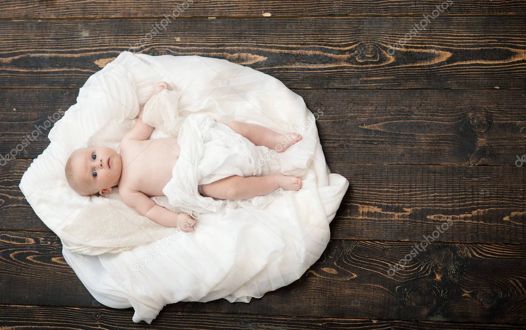 Newborn toddler with blue curious eyes on wooden background