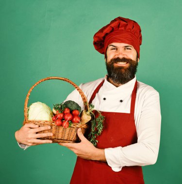 Şefin elinde lahana, turp, brokoli ve havuç var. Gülümseyerek yemek yap