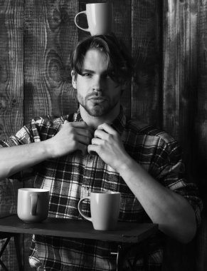 Ahşap arka planda bardakları tutan yakışıklı adam.