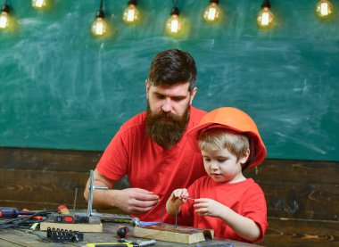 Tamirci ve atölye kavramı. Baba, üst araç tornavida kullanmak için küçük oğlu öğretim sakallı. Çocuk, Çocuk koruyucu kask babamla tornavida kullanmayı öğrenme içinde meşgul