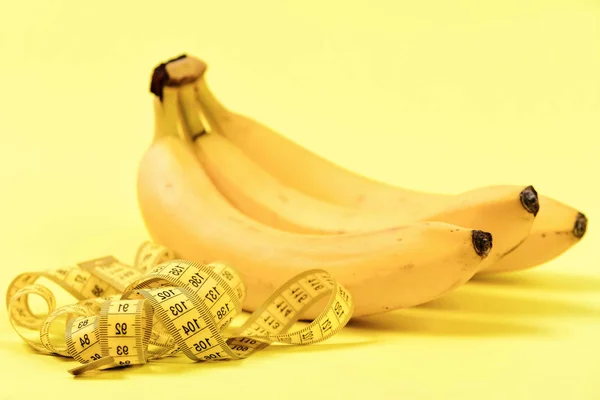 Лента для измерения рядом с кучей спелых бананов — стоковое фото