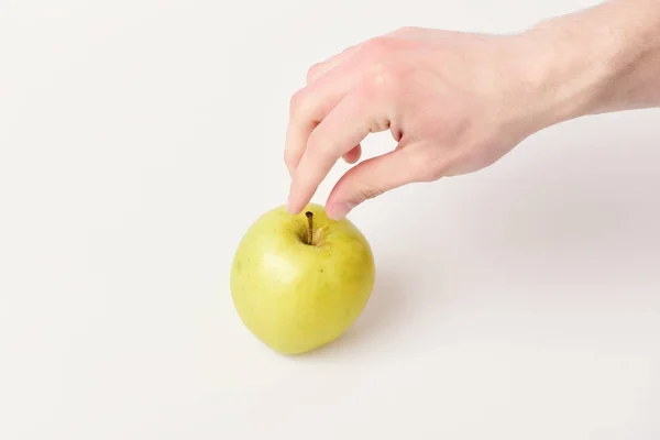 Мужская рука достигает светло-зеленого яблока. Яблочные фрукты на белом — стоковое фото
