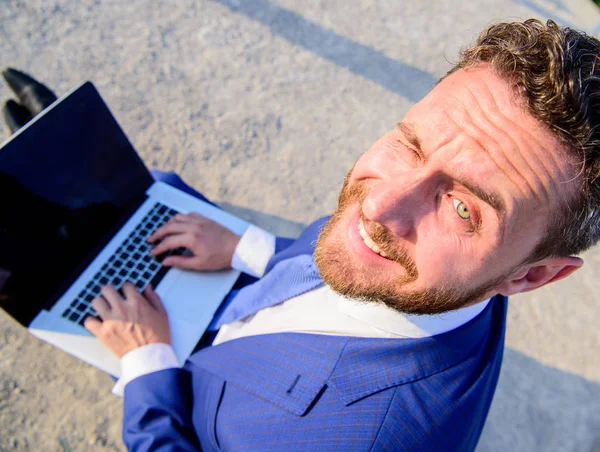 Man smiling cheerful face work with laptop close up. Businessman formal suit looks back while holds open screen laptop. Pleasant workday outdoors. Sunny summer day great opportunity to work outside