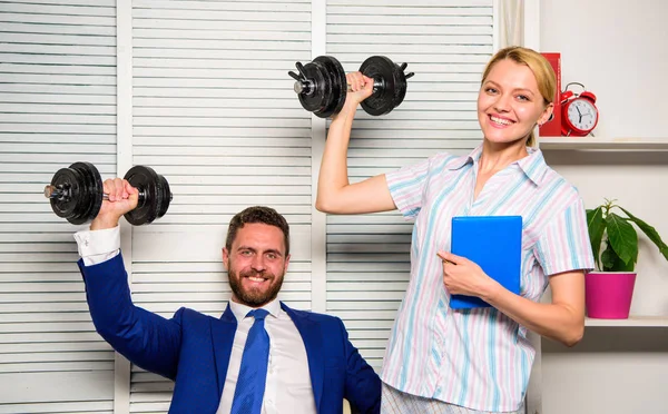 Boss businessman and office manager raise hand with dumbbells. Strong business team. Healthy habits in office. Man and woman raise heavy dumbbells. Strong powerful business strategy. Good job concept