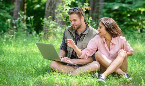 Homem e menina olhando para a tela do laptop. Os jovens de casal passam o lazer ao ar livre com computador portátil. As tecnologias modernas dão a oportunidade de estar online e trabalhar em qualquer condição ambiental. Oportunidade freelance — Fotografia de Stock