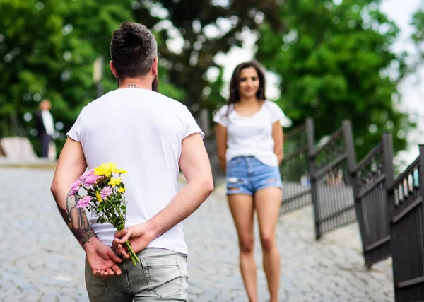 花束常に良いアイデア 紳士のマナー カップルの日パーク背景の会議 ガール フレンドのためのサプライズ花束を準備しました 待機の女の子デート中後ろの花の花束を非表示に — ストック写真