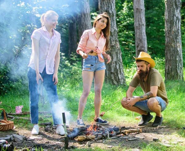 Faz uma pausa para comer qualquer coisa. Caminhantes da empresa em piquenique assar salsichas em paus. Amigos preparar salsichas assadas lanches fundo natureza. Camping refeição tradicional preparada em fogo com aroma fumegante — Fotografia de Stock