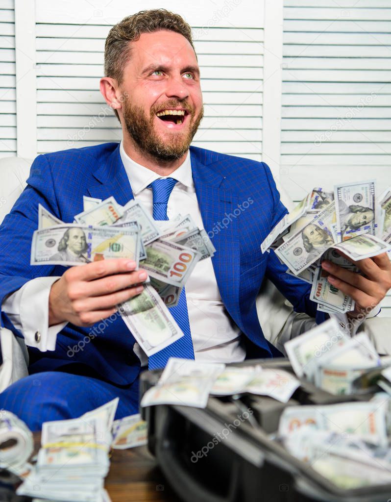 Man cheerful happy businessman with pile dollar banknotes. Profit and richness concept. Businessman formal suit hold cash dollars hands. Che k out my profit this month. Earn money easy business tips