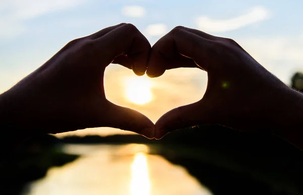 Naplemente napfény romantikus hangulatot. Kéz a szív megfelelő kézmozdulat-szimbólum a szeretet és a romantika. Szív gesztus folyó fölé naplemente előtt. Ötlet nászút utazás. Nászút nyári üdülőhely. Ötletek romantikus dátum — Stock Fotó