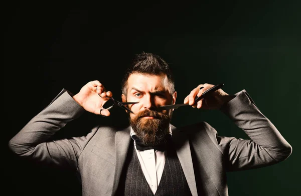 Uomo d'affari con una faccia seria su sfondo verde scuro. Macho in abito formale taglia e rasa barba e baffi . — Foto Stock