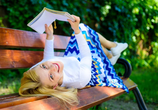 Леди счастливое лицо любит читать. Время самосовершенствоваться. Девушка лежала скамейка парк отдыха с книгой, зеленый фон природы. Девушка читает на открытом воздухе, расслабляясь на скамейке. Женщина проводит досуг с книгой — стоковое фото