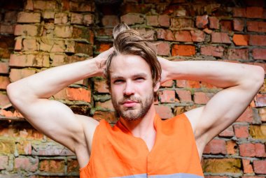 Adam tousled saç standı önünde duvarın dışında kırmızı tuğla yaptı. Oluşturucu Turuncu yelek şantiye inşaat. Seksi maço foreman. Her kadının Oluşturucusu seksi kaslı kolları maço rüya