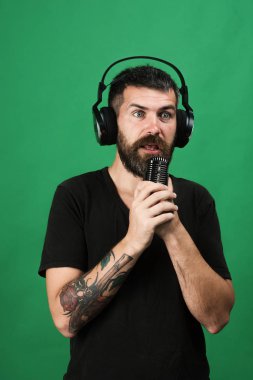 Zevk, müzik ve yaratıcı yaşam tarzı kavramı. Adam yeşil arka plan üzerinde mikrofon tutar. DJ sakallı
