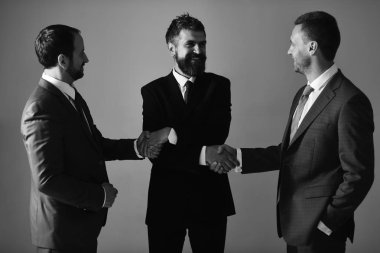 Erkeklerin sakal ve mutlu yüzler ile el sıkışan iş planları tartışmak. İşadamları akıllı takım elbise ve kravat giymek. Yöneticiler olun anlaşma