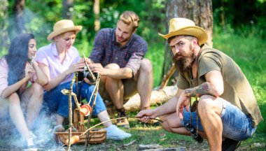 Arkadaşlar izlenim paylaşımı ve kamera fotoğrafları izlerken günlük üzerinde otururken sosis kavurma hippi. Arkadaş grubu turist şenlik ateşi rahatlatıcı. Atıştırma zamanı olan turistler ile yangın gıda kavrulmuş
