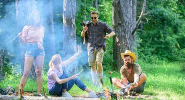 Büyük piknik için toplama. Şenlik ateşi takılmak ve hazırlamak için toplantı arkadaşlar sosis aperatifler doğa arka plan kavrulmuş. Yaz piknik katılın. Sosis sopa üzerinde kavurma sırasında eğlenmek Şirket