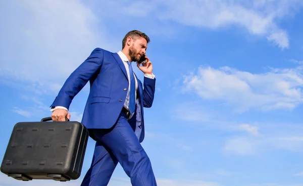 Keep going towards your goal. Businessman formal suit carries briefcase sky background. Entrepreneur in motion purposeful expression. Businessman solving business problems on phone. Never stop