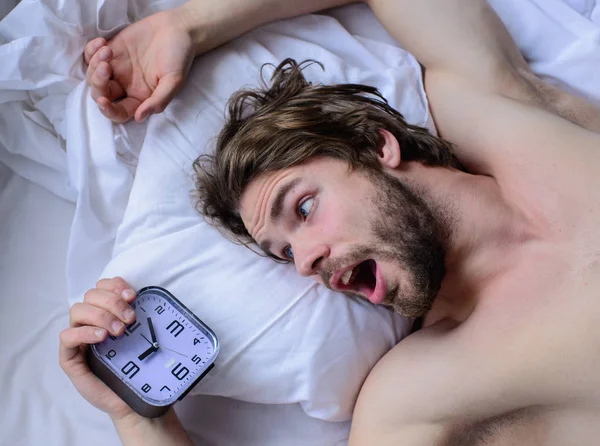 Oversleep again. Toughest part of morning simply getting out of bed. Man unshaven surprised shocked face lay pillow alarm clock top view. Guy missed alarm clock ringing. Get up early morning tips