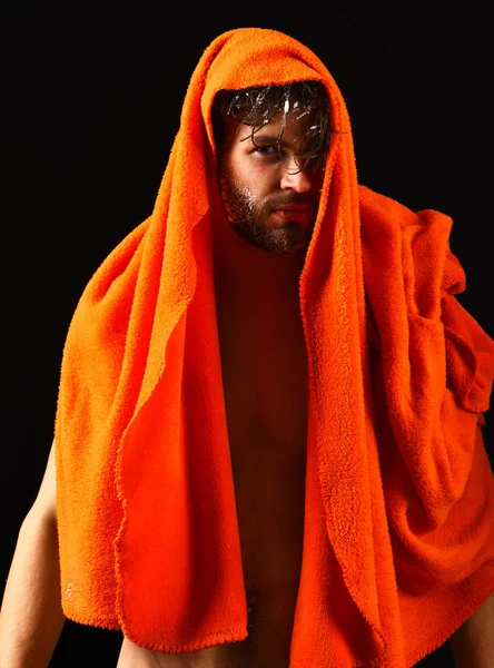 Man bearded tousled hair covered with foam soap suds. Macho attractive nude guy black background. Man with orange towel wipe hair. Wash off foam with water carefully. Apply conditioner after shower
