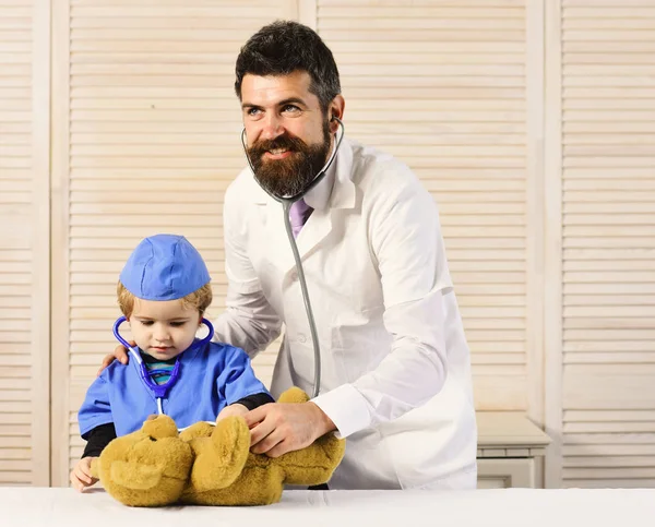 Sağlık ve çocukluk kavramı. Adam ve çocuk Stetoskoplar ahşap arka plan üzerinde tutun. — Stok fotoğraf