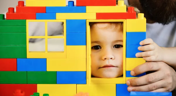 Criança fazendo uma nova casa de sonho com tijolos coloridos, olhando através da janela — Fotografia de Stock