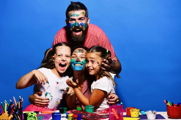 Padres e hijos pintados con gouache sobre fondo azul. Chicas, hombres y mujeres con caras alegres junto al escritorio de arte —  Fotos de Stock