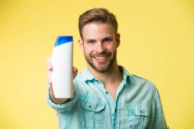 Adam şampuandan memnun kalmış. Sakallı adam plastik şişe tutuyor. Yakışıklı adam dış görünüşe önem verir kozmetik ya da hijyenik ürün kullanır. En sevdiği saç şampuanını göster.
