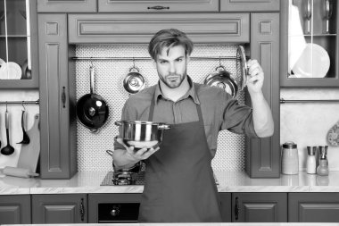 Aşçı adam tencereyi ve kapağı mutfakta tutuyor.