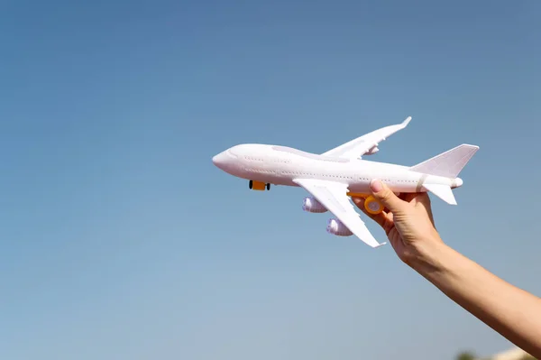 Plano en mano femenina claro cielo azul espacio de copia de fondo. Viajes y vacaciones. Reserve boletos ahora. Juguete blanco avión volar destinos de vacaciones. Viaja cómodas aerolíneas de clase premium. Descubre el mundo — Foto de Stock