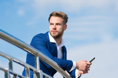 Ortağından önemli bir telefon bekliyorum. İş adamı video görüşmesi veya gökyüzü geçmişi için akıllı telefon kullanır. Takım elbiseli iş adamı modern mobil teknolojilerden iş için faydalanıyor.