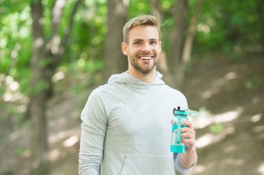 Atlet yüz tutun şişe bakım nemlendirici vücut egzersiz yaptıktan sonra memnun. Büyük iş sonra ferahlatıcı vitamin içeceği. Adam atletik görünüm su şişesi tutar. Sporcu içmek su maraton sonra