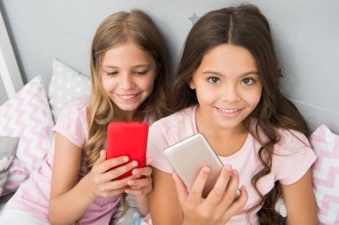 Pijama partisi konsepti. Kız kıza mutlu bir çocukluk. Akıllı telefonlu uzun saçlı kızlar modern teknoloji kullanır. Hadi selfie çekelim. Arkadaşlarının sosyal ağındaki fotoğrafını gönder. Çocuklar yatak odasında selfie çekiyor.